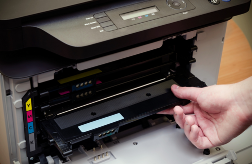 An employee changing out a ink cartridge from a printer supply company in Brighton.