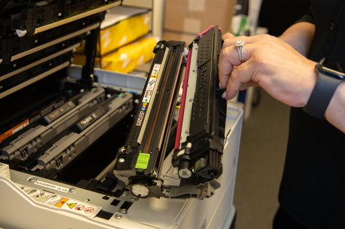 A woman changing and ink toner cartridge in her business class printer.